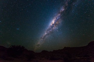 Samanyolu kemer, yıldızlar gökyüzünde, Namibya, Afrika Namib çölü. Sol taraftaki küçük Macellan Bulutu.