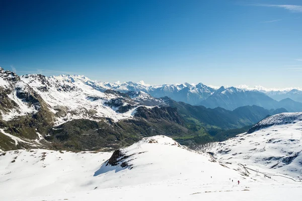 Wide angle view of a ski resort in the distance with elegant mountain peaks arising from the alpine arch in winter season. — Stock Photo, Image