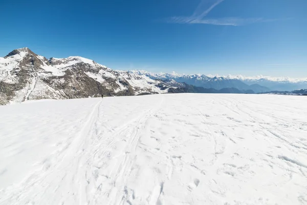 Широкий угол обзора горнолыжного курорта на расстоянии с элегантными горными вершинами, возникающими из альпийской арки в зимний сезон . — стоковое фото