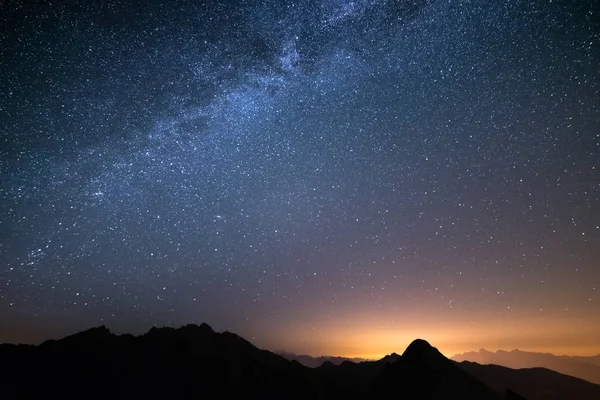 Noel zamanı ve parlayan köylerde aşağıda ile İtalyan Alplerinin ortasından görkemli yüksek Sıradağları üzerinde harika yıldızlı gökyüzü.