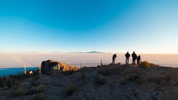 Uyuni tuz düz, güneş doğarken izlerken turistler seyahat hedef Bolivya. Geniş açı Incahuasi adanın zirvesinden ateş. — Stok fotoğraf