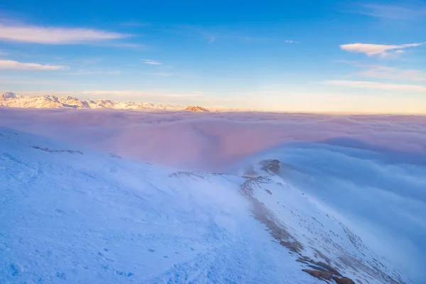 Malerische alpine Landschaft, Wolken im Tal arisign Berggipfel Sonnenuntergang Licht, Winter Schnee. — Stockfoto