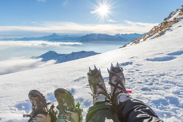 Pies en la cima de la montaña en contraluz. Bota de senderismo con crampones para escalada en hielo y nieve . — Foto de Stock