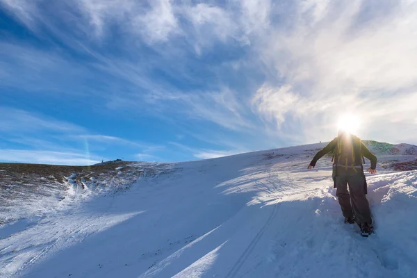 Mulher mochileiro trekking na neve nos Alpes. Visão traseira, estilo de vida de inverno, sensação de frio, estrela do sol na luz de fundo . — Fotografia de Stock