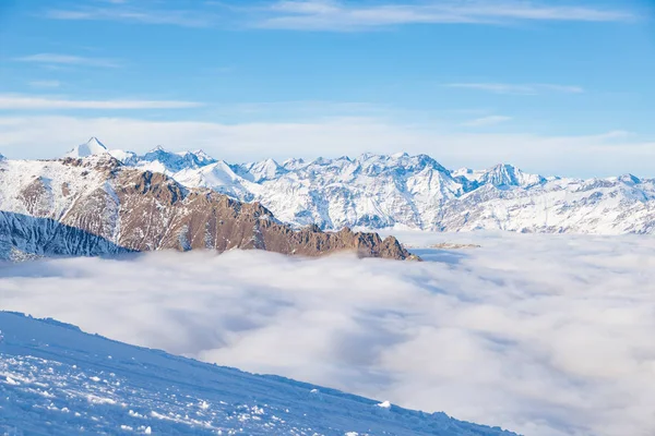 Paisaje alpino escénico, nubes en el valle arisign picos de montaña luz del atardecer, nieve de invierno . —  Fotos de Stock