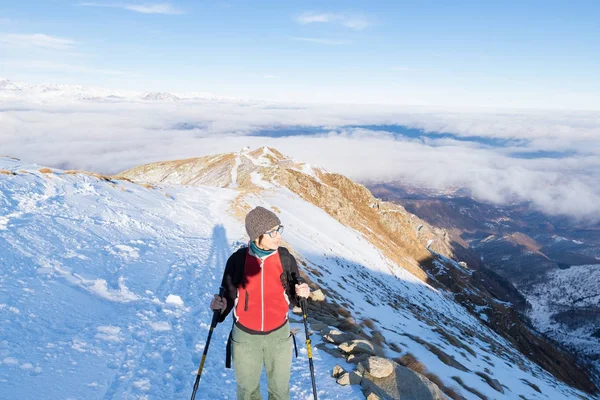 Backpacker kobiety trekking na śniegu w Alpach. Widok z tyłu, lifestyle zima, zimno uczucie, sun star w podświetlenie, kijki turystyczne. — Zdjęcie stockowe