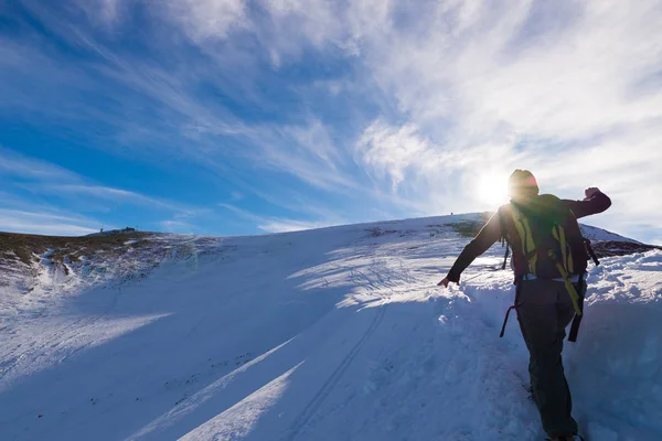 Γυναίκα backpacker πεζοπορία στο χιόνι στις Άλπεις. Οπίσθια όψη, lifestyle χειμώνα, κρύο συναίσθημα, sun star και με κόντρα φως. — Φωτογραφία Αρχείου