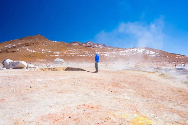 Tourist looking at steaming hot water ponds and mud pots in geothermal region of Huayllajc on the Andean Highlands of Bolivia. — Stock Photo, Image