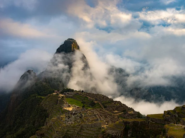 Machu Picchu iluminado pela primeira luz solar saindo das nuvens de abertura. A cidade do Inca é o destino de viagem mais visitado no Peru. Névoa, nuvens e nevoeiro que cobrem o vale . — Fotografia de Stock