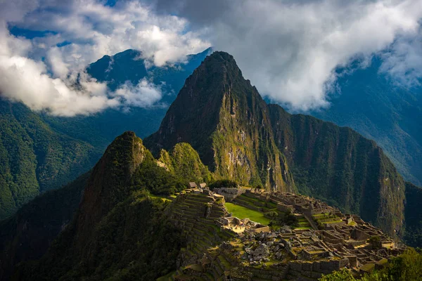 Machu Picchu iluminado por la primera luz del sol que sale de las nubes de apertura. La ciudad del Inca es el destino turístico más visitado en Perú. Niebla, nubes y niebla que cubren el valle . — Foto de Stock