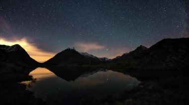 Yıldızlı gökyüzü ve Orion zaman atlamalı karlı dağ sırtı, pastoral dağ Gölü üzerinde yansıma ötesinde Alpler üzerinde.