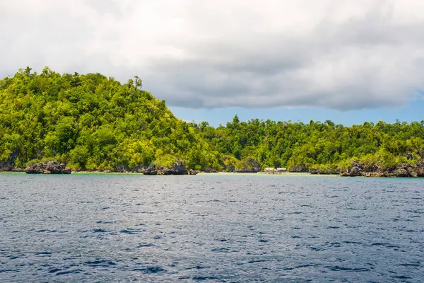 Rocky coastline of island spotted by islets and covered by dense lush green jungle in the colorful sea of the remote Togean Islands (or Togian Islands), Central Sulawesi, Indonesia. — Stock Photo, Image