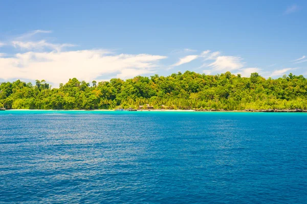 Rocky coastline of island spotted by islets and covered by dense lush green jungle in the colorful sea of the remote Togean Islands (or Togian Islands), Central Sulawesi, Indonesia. — Stock Photo, Image