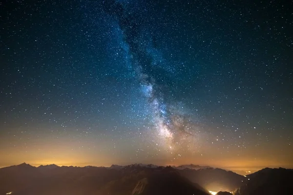 Via Láctea e céu estrelado capturado em alta altitude no verão nos Alpes com brilho Aosta Valley abaixo, destino de viagem na Itália . — Fotografia de Stock