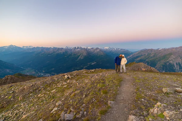 Couple of people looking at the sunrise over Mont Blanc mountain peak (4810 m). Valle d'Aosta, italian summer adventures and travel destination on the Alps. — Stock Photo, Image