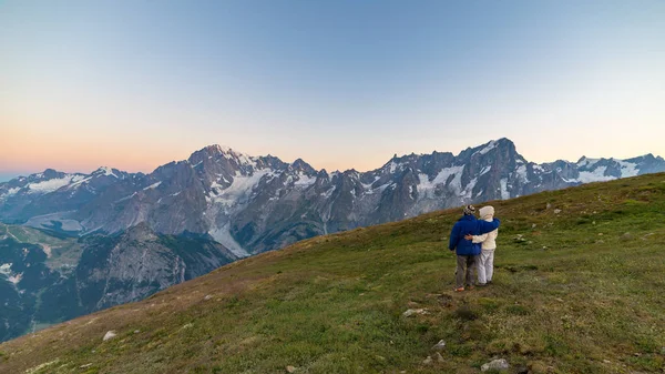 Couple of people looking at the sunrise over Mont Blanc mountain peak (4810 m). Valle d'Aosta, italian summer adventures and travel destination on the Alps. — Stock Photo, Image