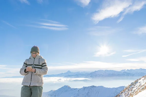 A nő segítségével okos telefon, a hegyekben. Panoráma a snowcapped Alpok, hideg téli szezonban. Fogalmának közös élet pillanatait, új technológiák használata. — Stock Fotó