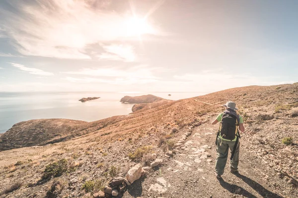 背包客在阳光岛上探索印加小径, 的的喀喀湖湖, 在玻利维亚旅游胜地。在美洲旅行冒险和度假。色调的图像, 背光, 太阳. — 图库照片