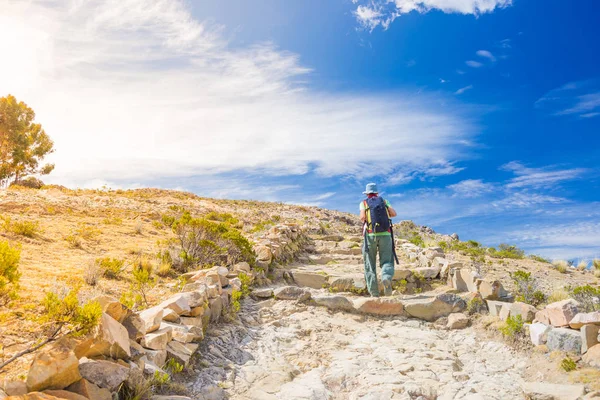 Backpacker explora el Camino Inca en la Isla del Sol, Lago Titicaca, destino turístico escénico en Bolivia. Aventuras de viaje y vacaciones en las Américas. Imagen tonificada, contraluz, sol . — Foto de Stock