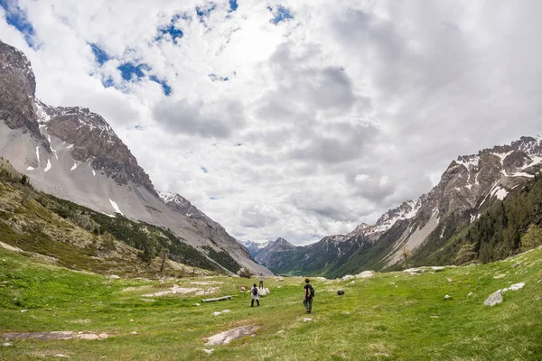 Escursionisti in salita su ripido sentiero roccioso di montagna. Avventure estive ed esplorazioni sulle Alpi. Cielo drammatico con nuvole di tempesta . — Foto Stock