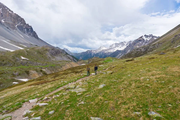 Caminhantes subindo colina acima em trilha de montanha rochosa íngreme. Aventuras de verão e exploração nos Alpes. Céu dramático com nuvens de tempestade . — Fotografia de Stock