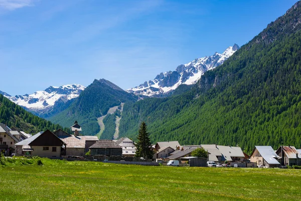 Summer in the Alps, tourist resort, vacation village. Blooming alpine meadow and lush green woodland set amid high altitude mountain range. — Stock Photo, Image