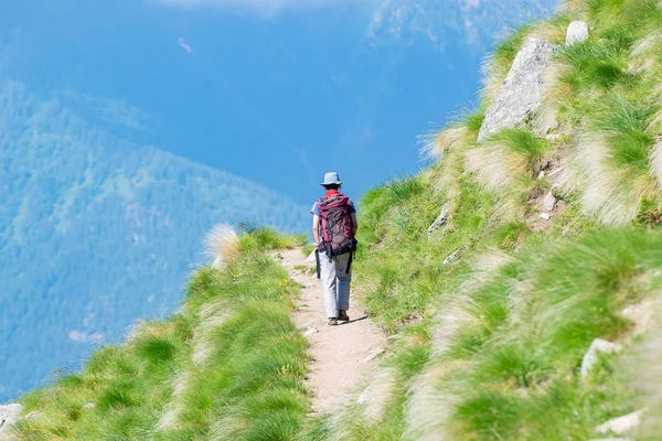 Mochilero caminando por senderos en la montaña. Aventuras de verano vacaciones de verano en los Alpes. Gente vagabunda viajando concepto . — Foto de Stock