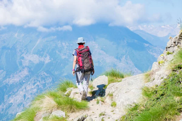 Backpacker walking on hiking trail in the mountain. Summer adventures summer vacation on the Alps. Wanderlust people traveling concept. — Stock Photo, Image