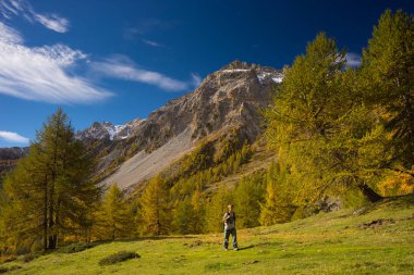 Muhteşem panoramik manzarası ve canlı renkler ile renkli bir vadi üzerinde yürüyen uzun yürüyüşe çıkan kimse. İtalyan Fransız Alps geniş açı çekim.