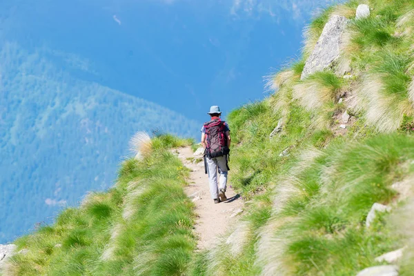 Backpacker walking on hiking trail in the mountain. Summer adventures summer vacation on the Alps. Wanderlust people traveling concept. — Stock Photo, Image