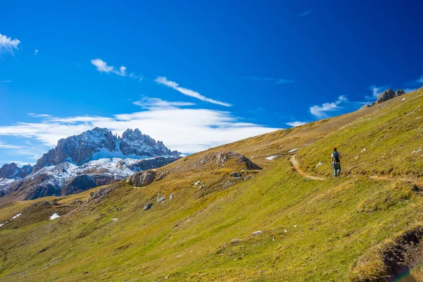 Hiker walking on a colorful valley with great panoramic view and vivid colors. Wide angle shot in the Italian French Alps. — Stock Photo, Image