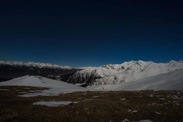 Vista nocturna del cielo estrellado en los Alpes. Cordillera nevada a la luz de la luna . — Foto de Stock