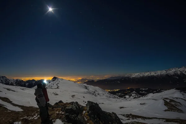 Luna y cielo estrellado, nieve en los Alpes, lente de ojo de pez. Constelación de Orión, Betelgeuse y Sirio. Larga exposición borrosa dos excursionistas mirando a la vista, actividades nocturnas al aire libre . — Foto de Stock