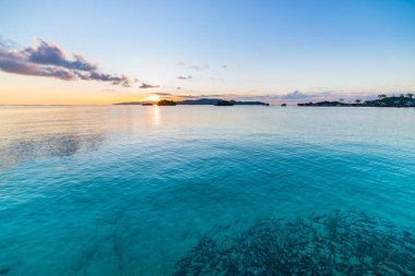 Togean Adaları Sunrise, Togian Adaları seyahat hedef, Sulawesi, Endonezya. Şeffaf turkuaz suda ıslatın ve dağınık adacıkları balık sürüsü.