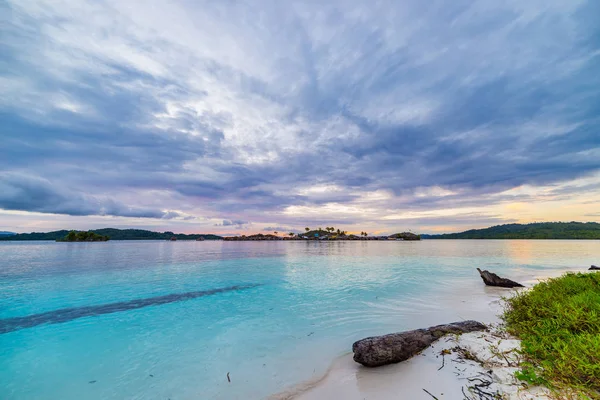 Pantai tropis, laut Karibia, air pirus transparan, Pulau Togean terpencil (Kepulauan Togian), Sulawesi, Indonesia. Dramatis langit saat matahari terbenam . — Stok Foto