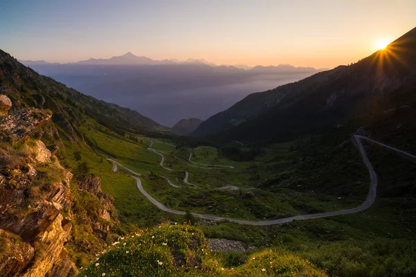 Chemin de montagne menant au col de haute montagne en Italie (Colle delle Finestre). Vue expansive au coucher du soleil, ciel spectaculaire coloré, aventures en été, Alpes italiennes . — Photo