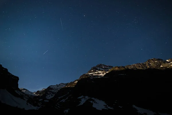 Stjärnhimlen på Alperna upplyst av moonlight. Expansiva natt liggande bred vy. — Stockfoto