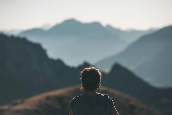 Uma pessoa olhando para a vista majestosa de picos de montanha brilhantes ao pôr do sol no alto dos Alpes. Visão traseira, imagem tonificada e filtrada, foco no fundo . — Fotografia de Stock