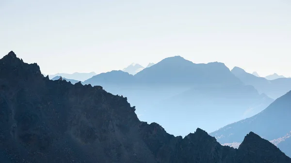 Distant mountain silhouette with clear sky and soft light. Toned image, vintage filter, split toning. — Stock Photo, Image