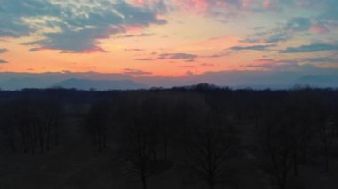 Hava: kırsal, orman ormanlık ve doğal parkı yukarıdan, günbatımı renkli gökyüzü üzerinde Alps, Piedmont, İtalya uçan.