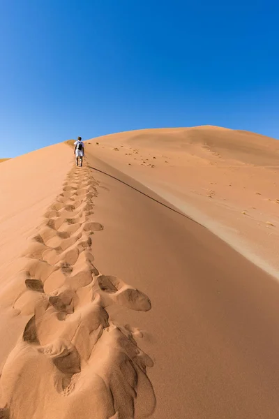Turista caminando por las dunas pintorescas de Sossusvlei, desierto de Namib, Parque Nacional de Namib Naukluft, Namibia. Aventura y exploración en África . — Foto de Stock