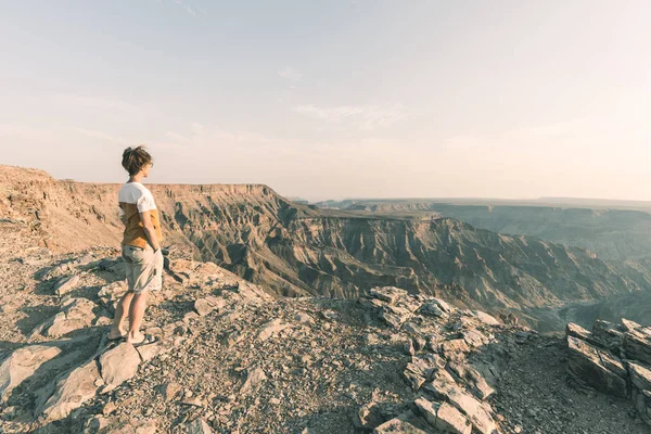 Uma pessoa olhando para o Fish River Canyon, destino de viagem cênica no sul da Namíbia. Vista expansiva ao pôr do sol. Wanderlust viajando pessoas . — Fotografia de Stock