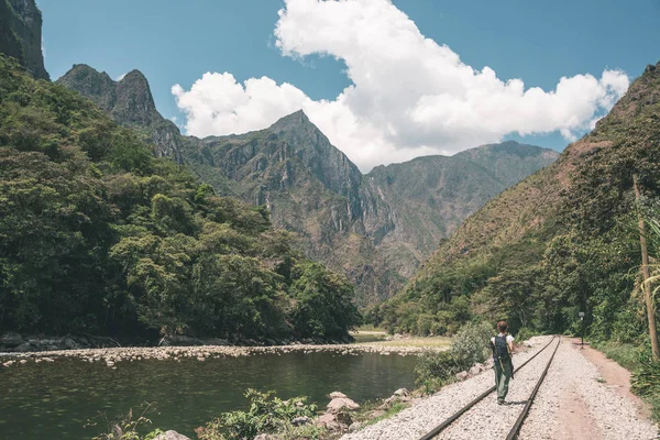 Mochilero caminando en la vía férrea a Machu Picchu, Perú, alternativa a la conexión de tren turístico habitual. Machu Picchu sitio arqueológico principal destino de viaje. Imagen tonificada . — Foto de Stock