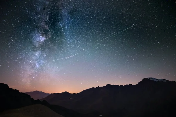 Galaxia de la Vía Láctea y cielo estrellado desde una gran elevación en verano en los Alpes. Tráfico aéreo, luces de la ciudad . — Foto de Stock