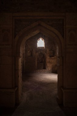 Mandu India, afghan ruins of islam kingdom, palace interior, mosque monument and muslim tomb. Sunshine from door in dark corridor. clipart