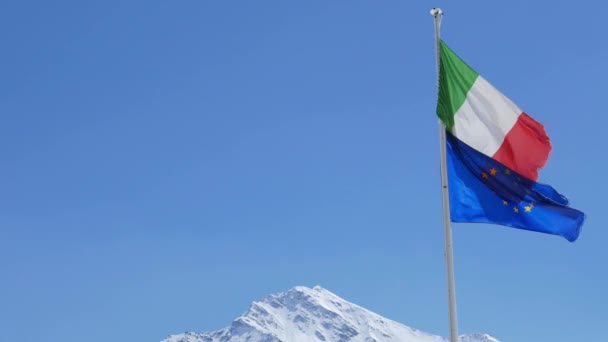 欧洲联盟和意大利国旗吹在阿尔卑斯山上 晴朗湛蓝的天空 — 图库视频影像