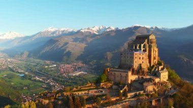 Hava: eski ortaçağ abbey adlı uçan uçak gündoğumu, arka plan karlı Alp dağ üstüne tünemiş. Sacra di San Michele (İtalyan) - Saint Michel Abbey (İngilizce traslation) - Torino, İtalya 