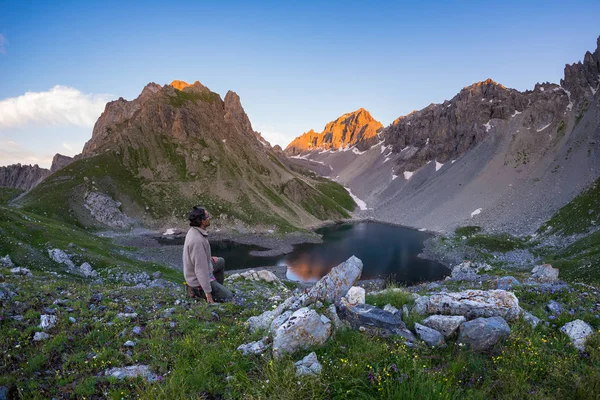 Backpacker turistiky na chodník a při pohledu na expanzivní pohled shora. Letní dobrodružství a průzkum v italských Alpách. — Stock fotografie