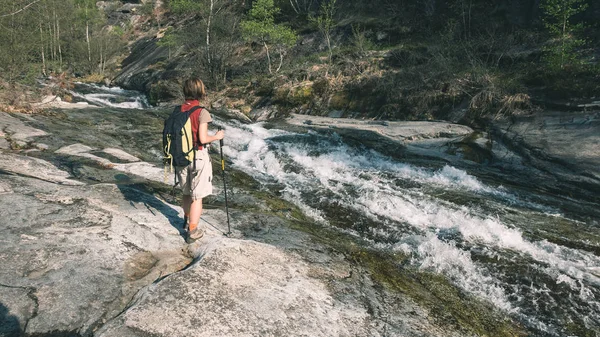 Mulher mochileiro andando na rocha explorando cachoeira no vale alpino, conceito de viagem mochila liberdade — Fotografia de Stock