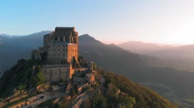 Hava: eski ortaçağ abbey adlı uçan uçak gündoğumu, arka plan karlı Alp dağ üstüne tünemiş. Sacra di San Michele (İtalyan) - Saint Michel Abbey (İngilizce traslation) - Torino, İtalya 
